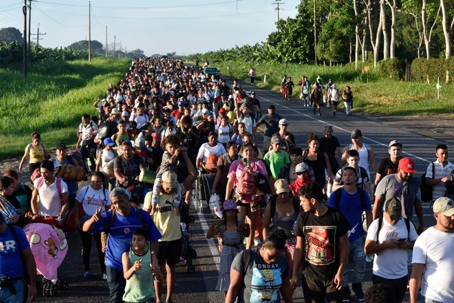 About 3,000 people carrying bags, water and small children trod through intense heat along a highway in southern Mexico on Tuesday, traveling in two groups aiming to reach the US border.